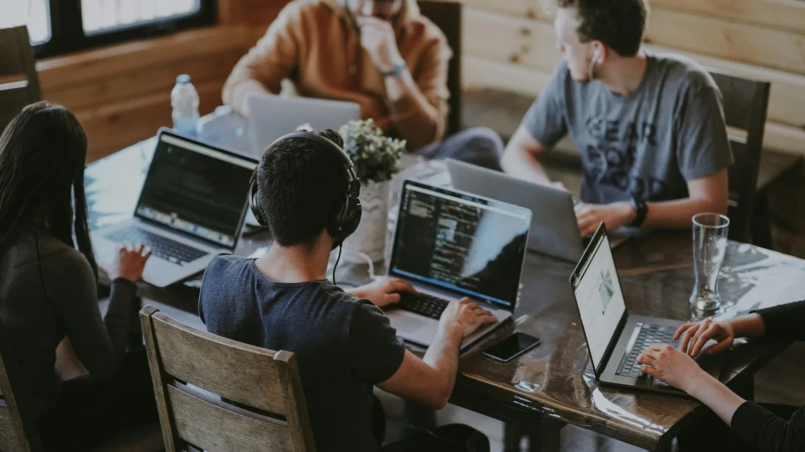 Team working on laptops together in a wood-paneled room