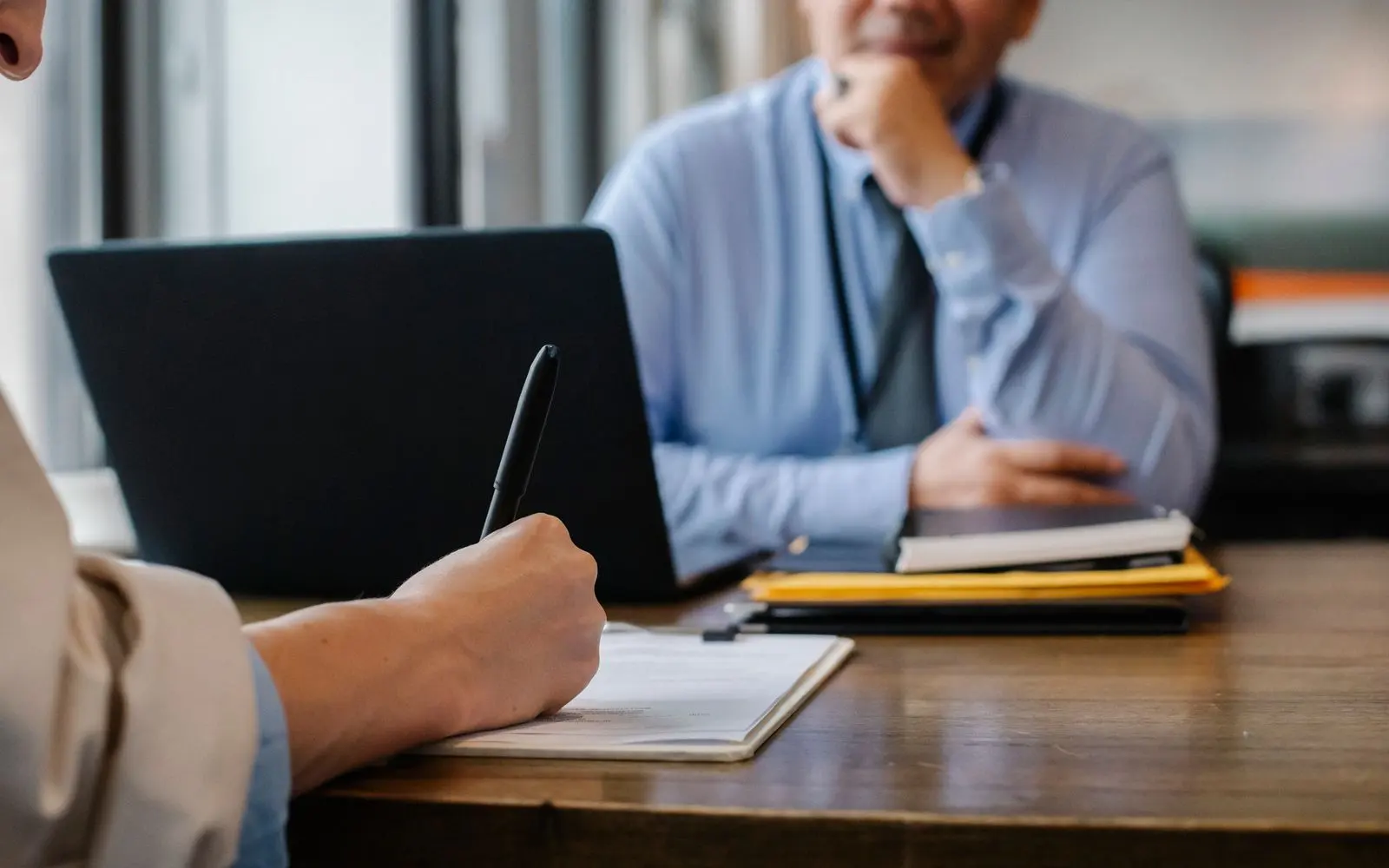 Recruiter taking notes across from a candidate during an interview