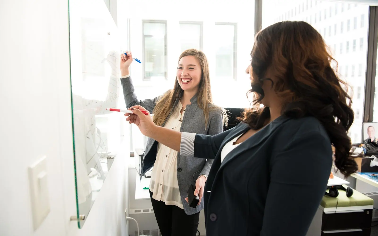 Two colleagues mapping a plan on a glass board